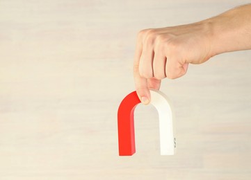 Photo of Man holding horseshoe magnet against light background, closeup. Space for text