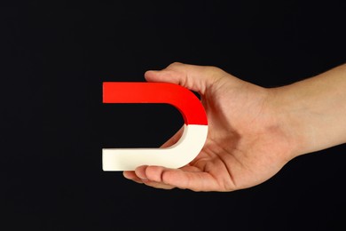 Photo of Man holding horseshoe magnet on dark background, closeup