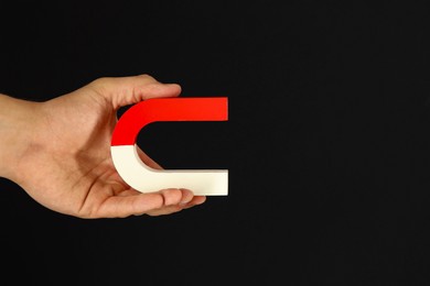 Photo of Man holding horseshoe magnet on dark background, closeup. Space for text