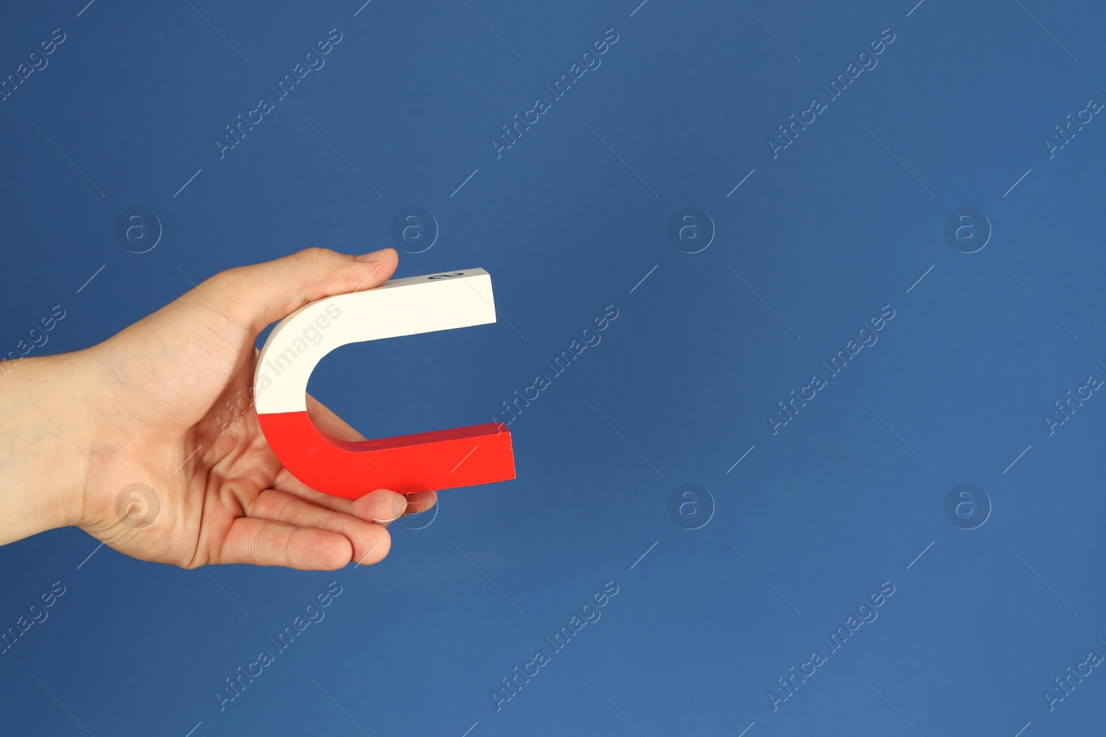 Photo of Man holding horseshoe magnet on blue background, closeup. Space for text