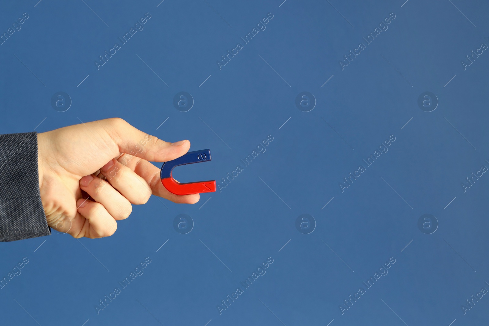 Photo of Man holding horseshoe magnet on blue background, closeup. Space for text