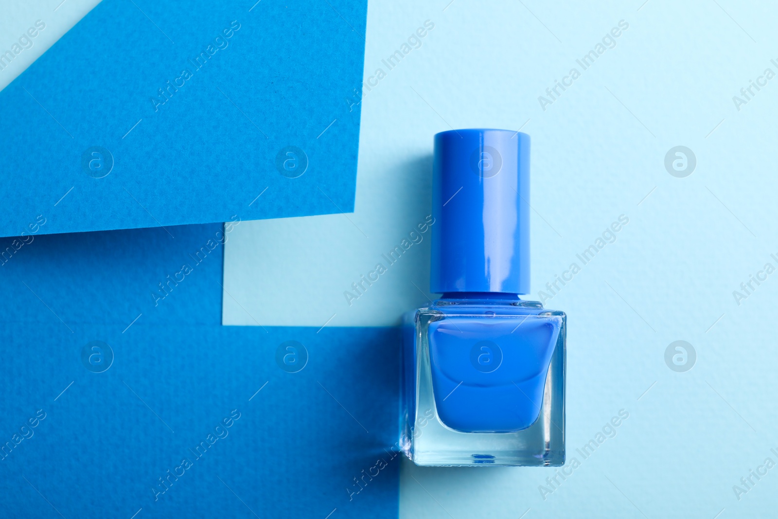 Photo of Nail polish in bottle on color background, top view. Space for text