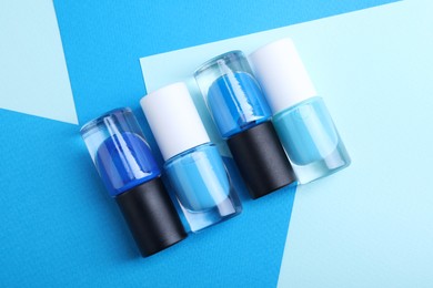 Photo of Nail polishes in bottles on color background, flat lay