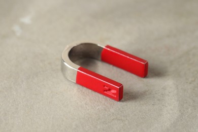 Photo of One horseshoe magnet on grey textured table, closeup