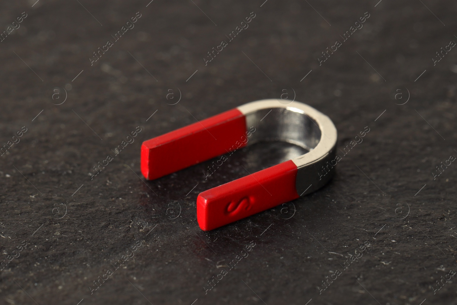 Photo of One horseshoe magnet on dark textured table, closeup