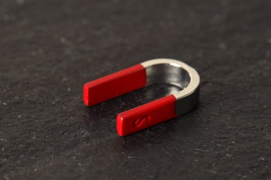 Photo of One horseshoe magnet on dark textured table, closeup