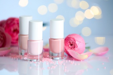 Photo of Nail polishes in bottles, beads and beautiful flowers on white table, closeup. Space for text