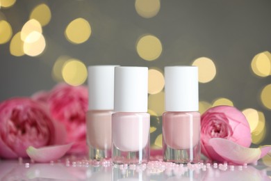 Photo of Nail polishes in bottles and beads on white table, closeup