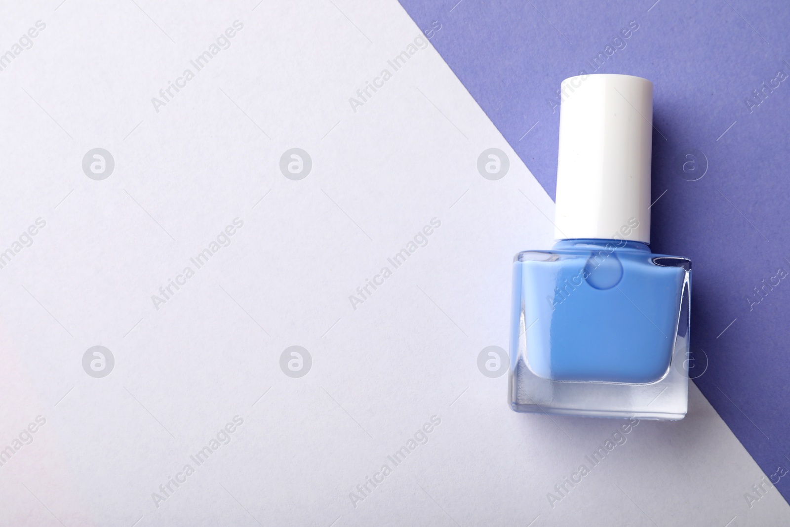 Photo of Nail polish in bottle on color background, top view. Space for text