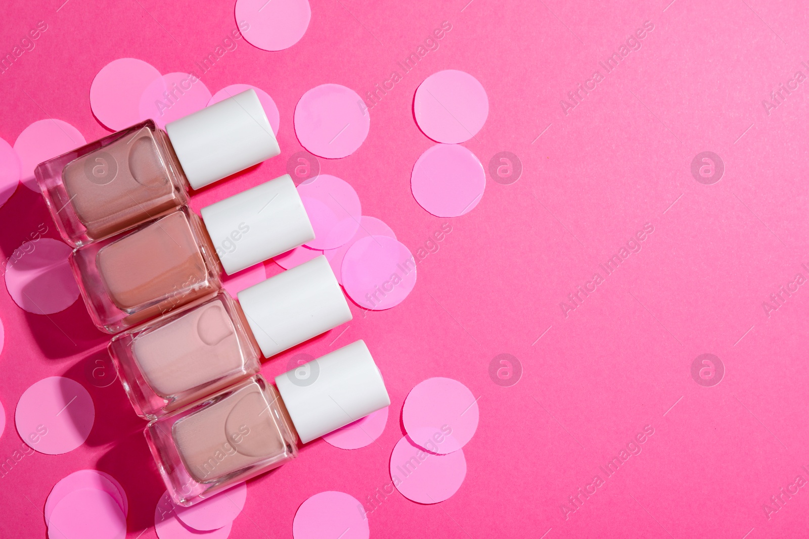 Photo of Set of nude nail polishes in bottles on pink background, flat lay. Space for text