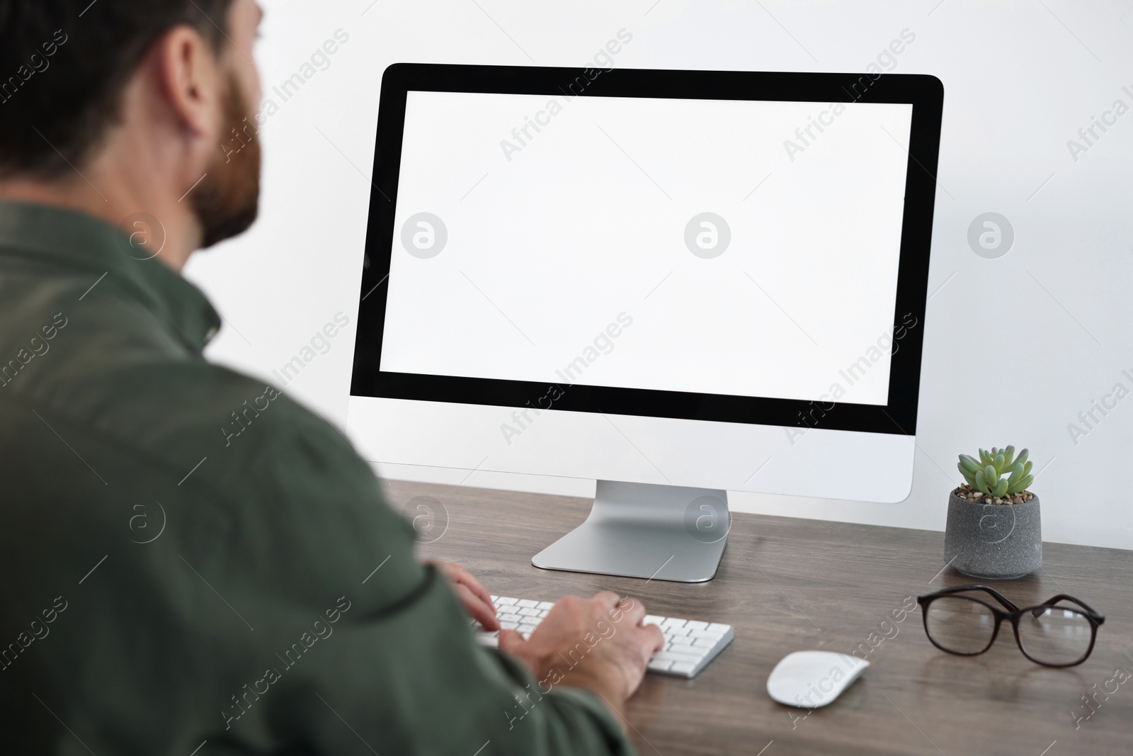 Photo of Man working on computer at table in office, closeup