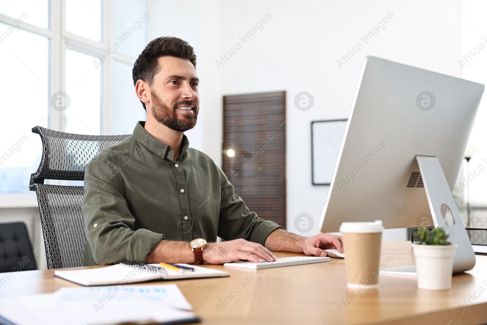 Photo of Man working on computer at table in office