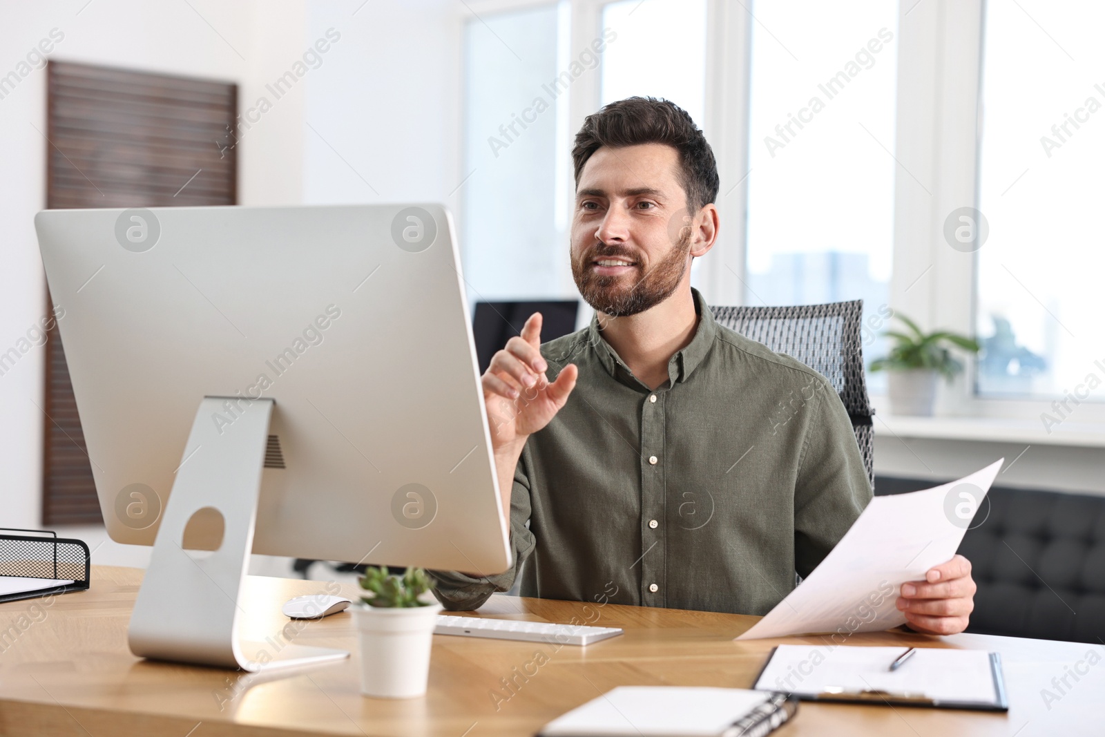 Photo of Man with document working at table in office