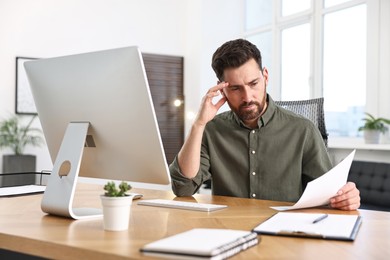 Photo of Man with document working at table in office