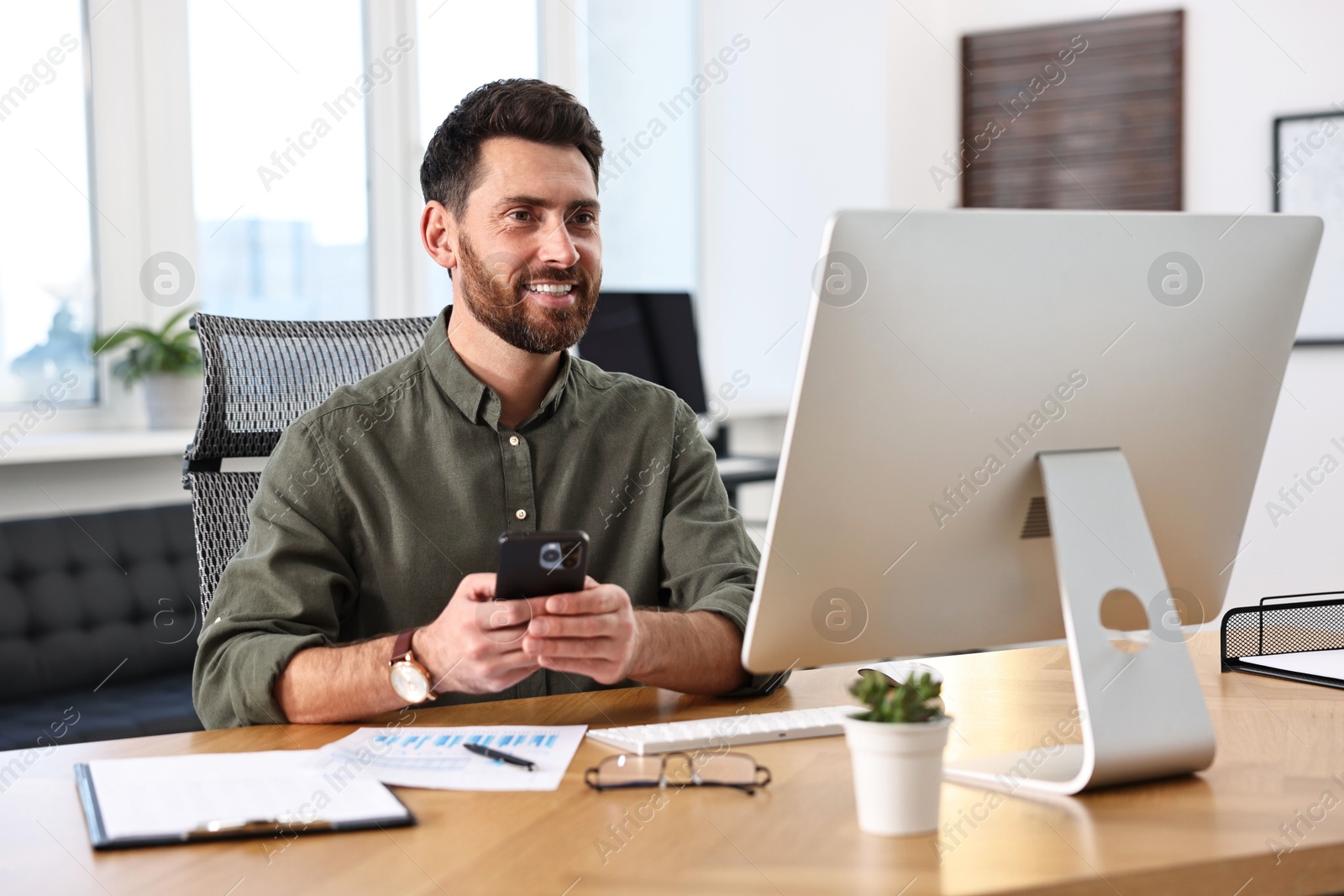 Photo of Man using smartphone at table in office