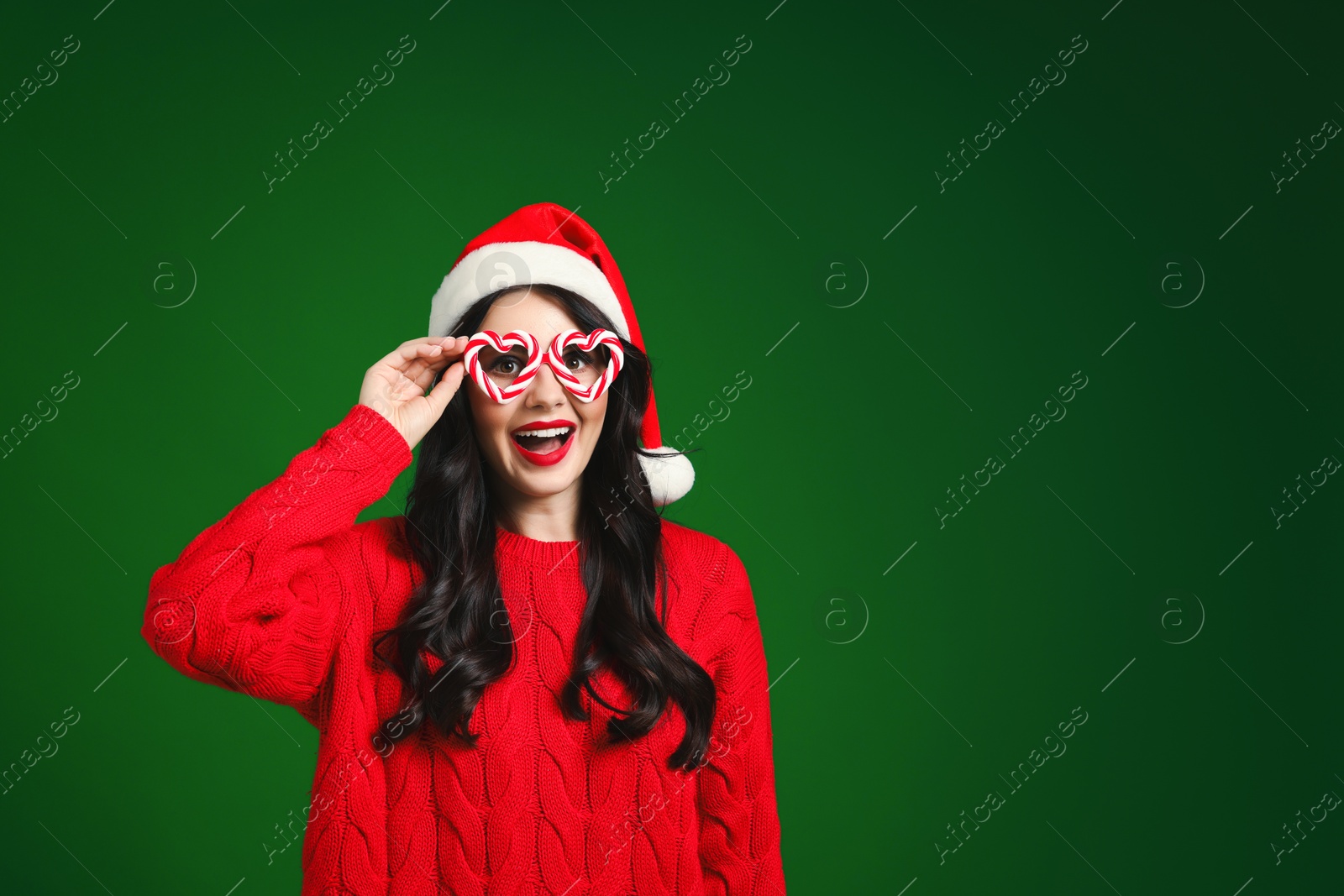 Photo of Beautiful woman in Santa hat and party glasses on green background, space for text. Christmas celebration