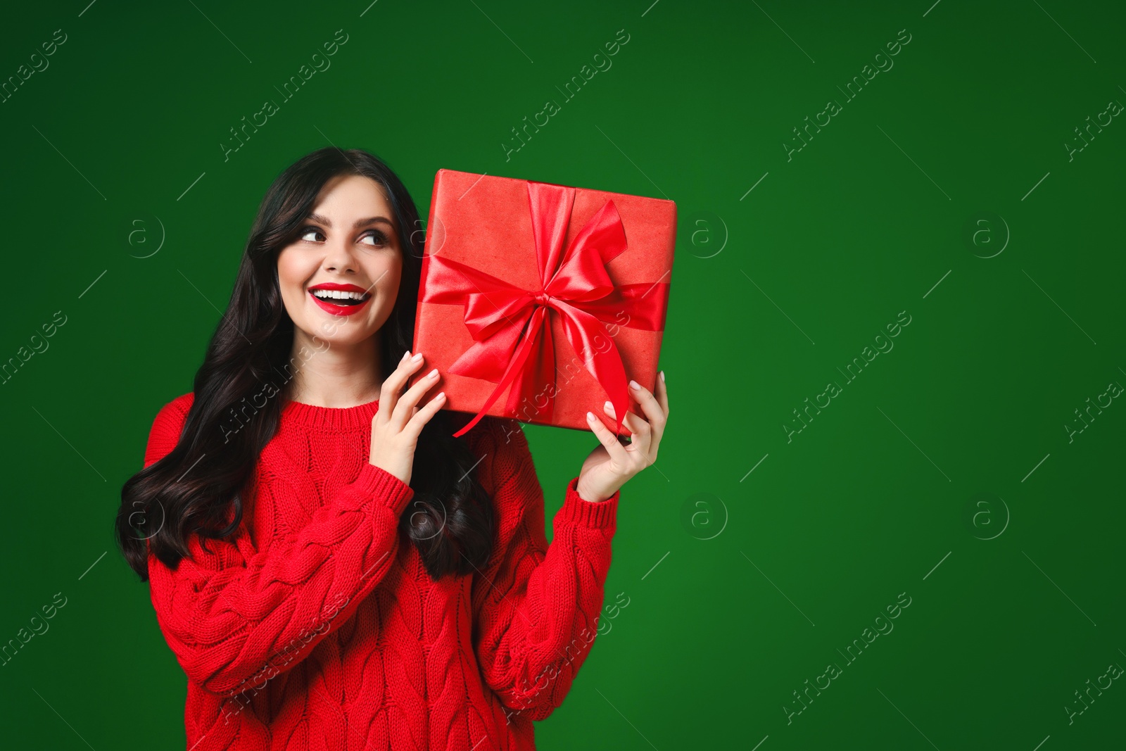 Photo of Beautiful woman with Christmas gift on green background, space for text