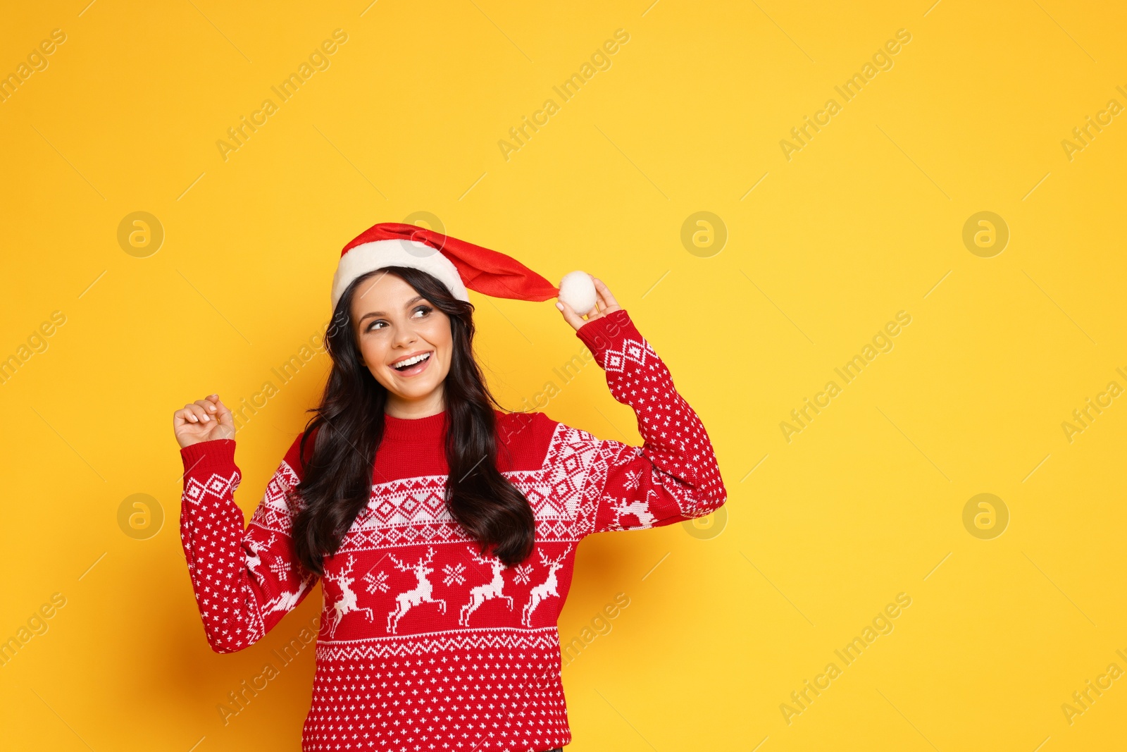 Photo of Beautiful woman in Santa hat and Christmas sweater on yellow background, space for text