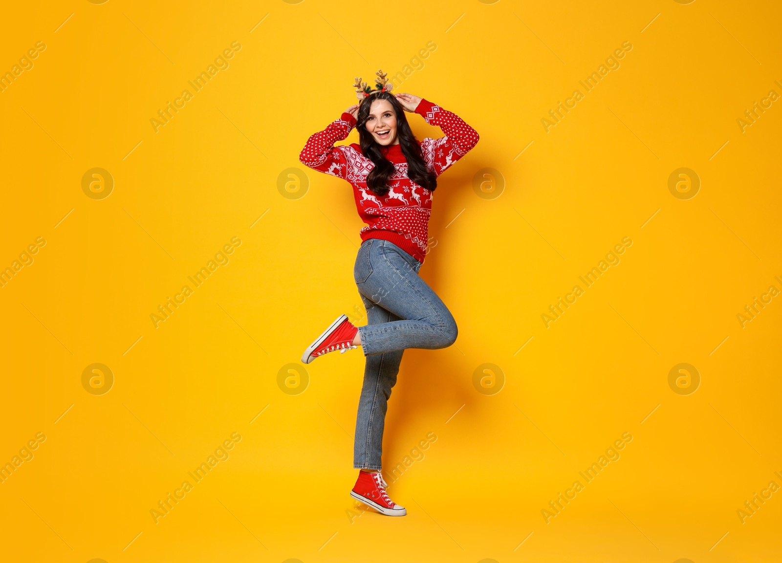 Photo of Beautiful woman in Christmas sweater and headband on yellow background