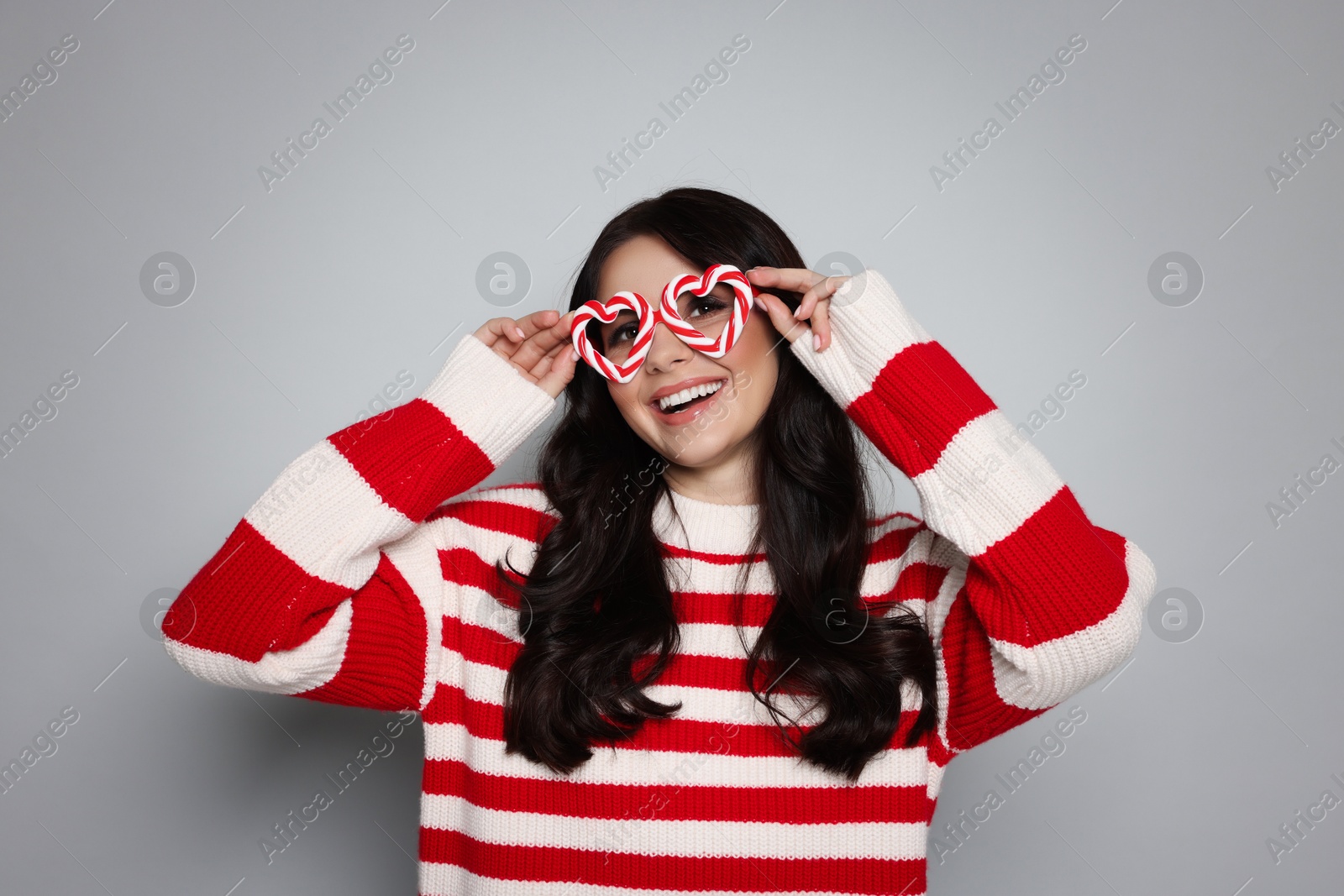 Photo of Happy woman with party glasses on light grey background. Christmas celebration