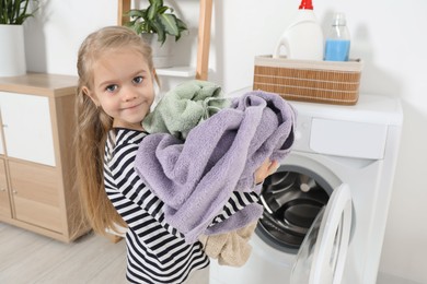 Photo of Little helper. Cute girl doing laundry at home