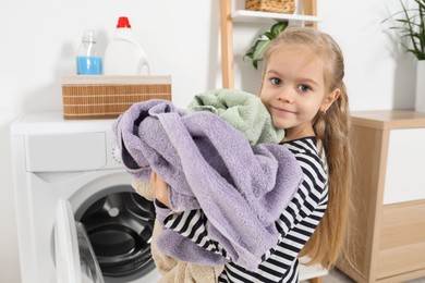 Photo of Little helper. Cute girl doing laundry at home