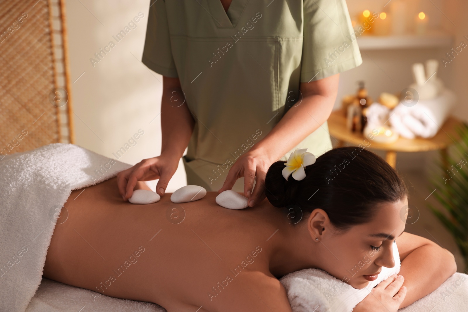 Photo of Woman receiving hot stone massage in spa salon