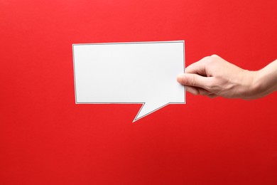 Photo of Woman holding blank speech bubble on red background, closeup. Space for text