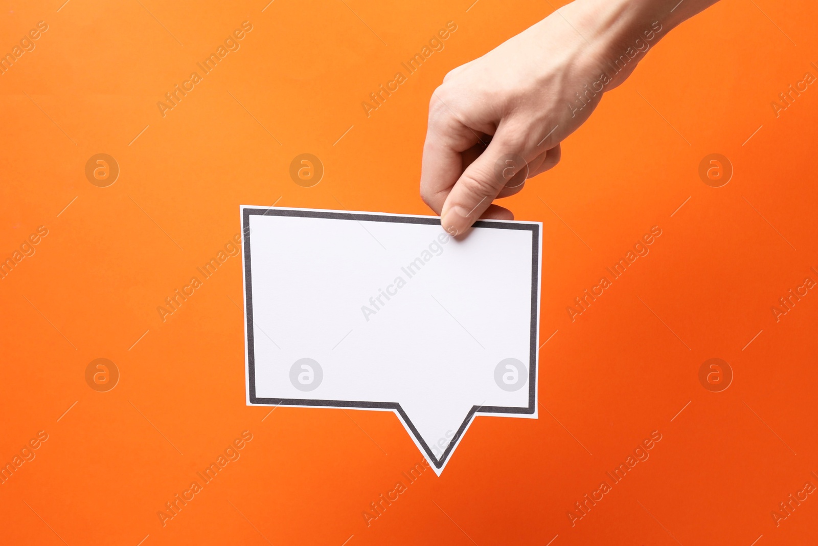 Photo of Woman holding blank speech bubble on orange background, closeup. Space for text