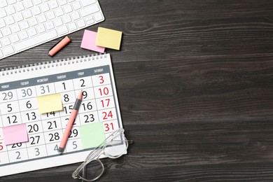 Photo of Timetable. Calendar, stationery and computer keyboard on wooden table, flat lay. Space for text