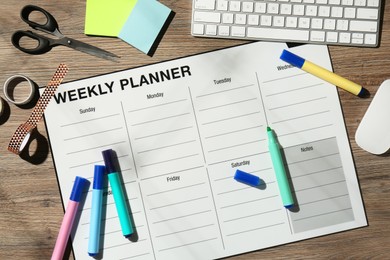 Photo of Timetable. Weekly planner, stationery and computer keyboard on wooden table, flat lay