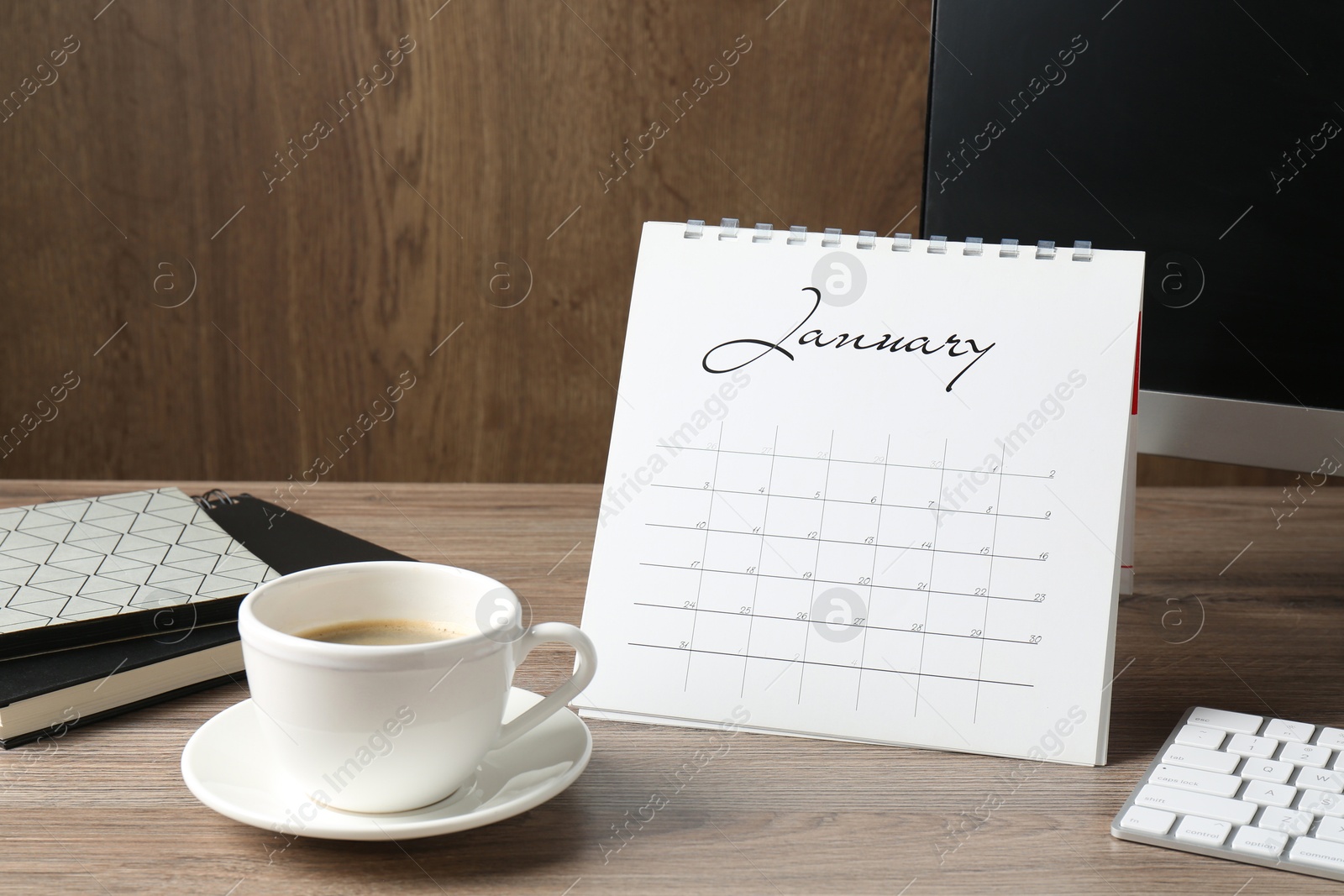 Photo of Timetable. Monthly planner, coffee, stationery and computer on wooden table