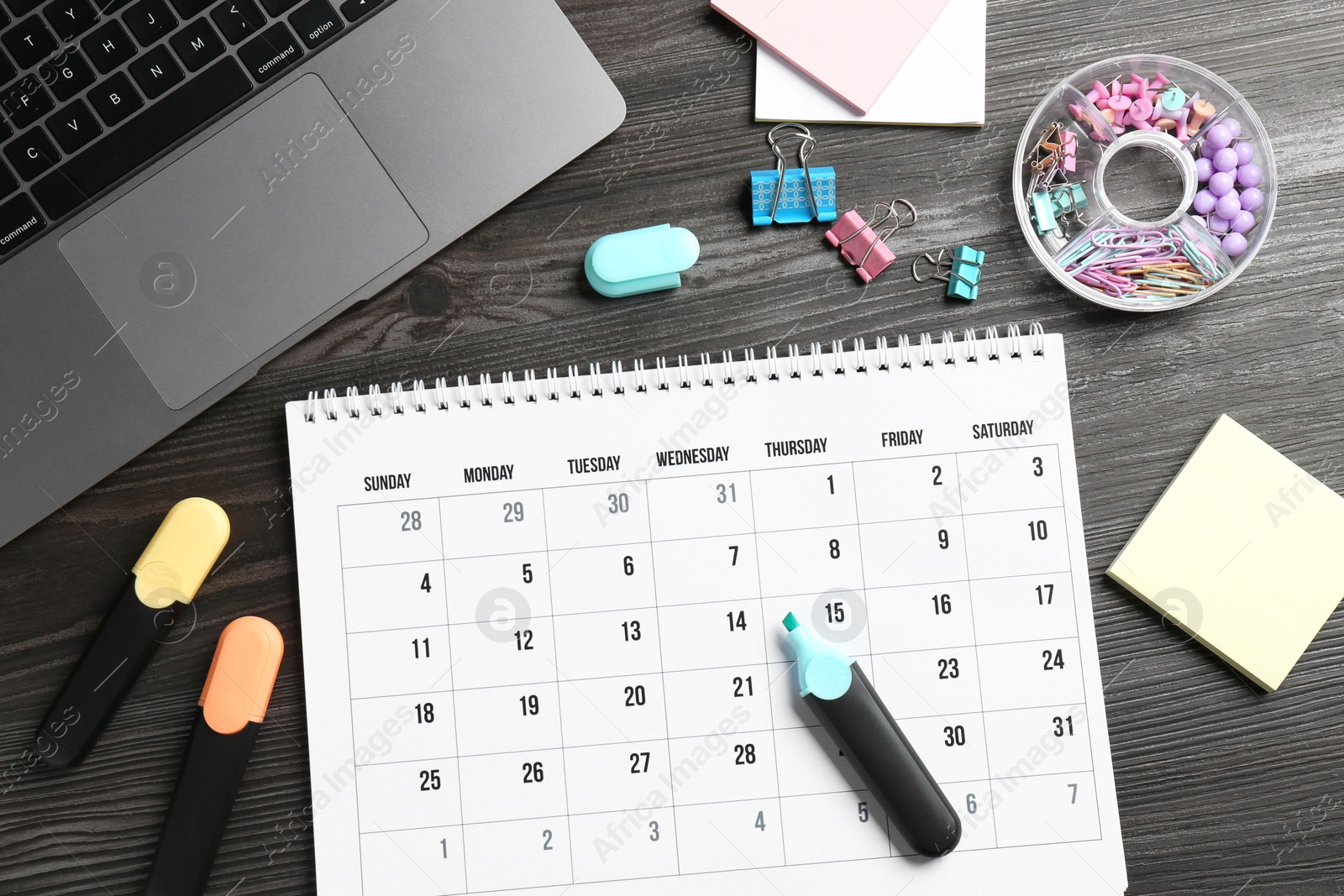 Photo of Timetable. Monthly planner, stationery and laptop on wooden table, flat lay