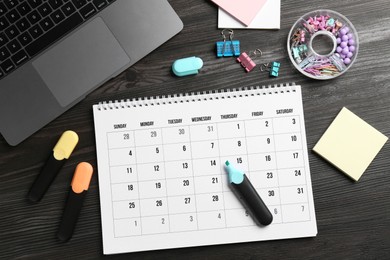 Photo of Timetable. Monthly planner, stationery and laptop on wooden table, flat lay