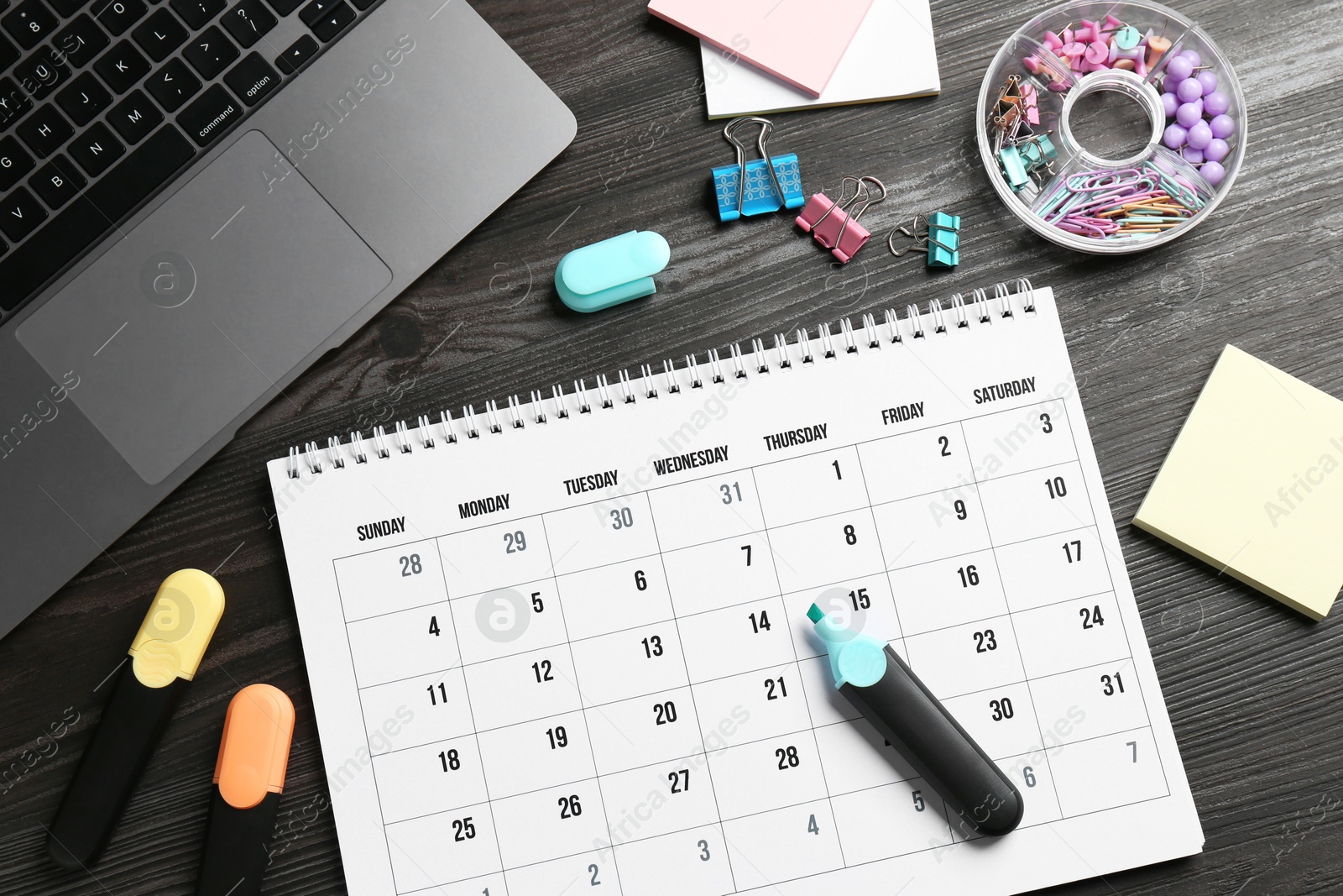 Photo of Timetable. Monthly planner, stationery and laptop on wooden table, flat lay