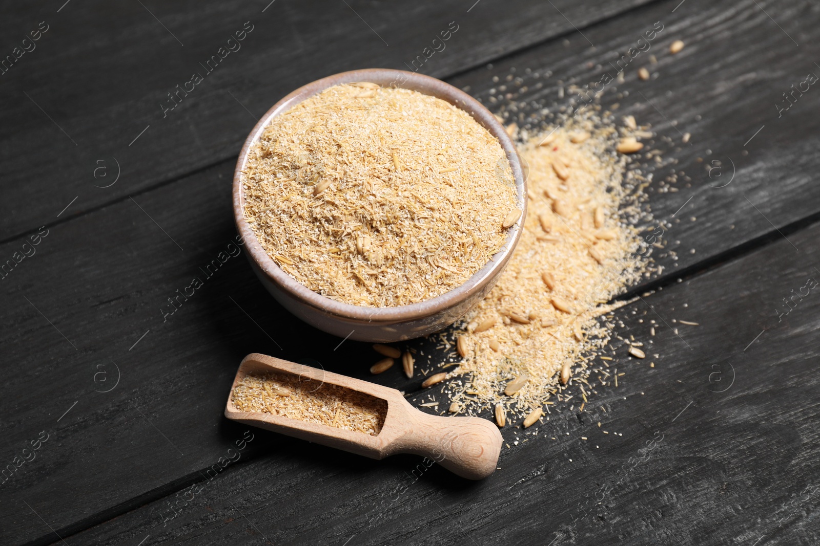 Photo of Oat bran in bowl, grains and scoop on black wooden table