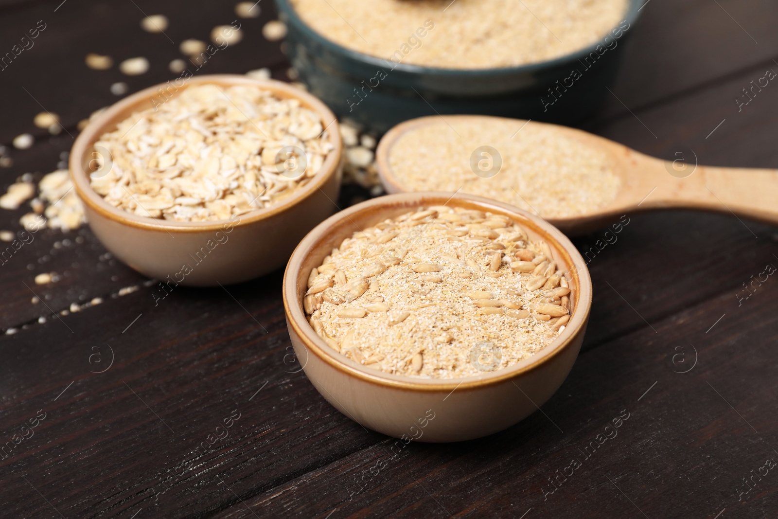 Photo of Oat bran, grains and flakes on wooden table, closeup