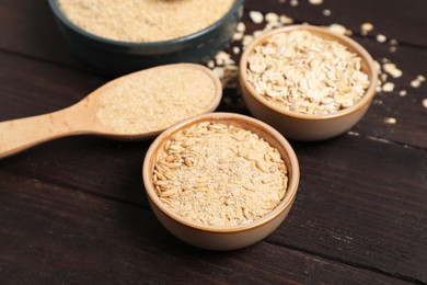 Photo of Oat bran, grains and flakes on wooden table, closeup