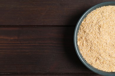 Photo of Oat bran in bowl on wooden table, top view. Space for text