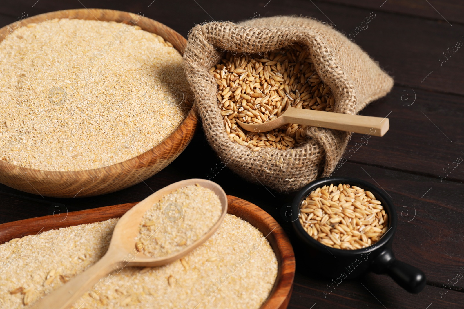 Photo of Oat bran and grains on wooden table, closeup