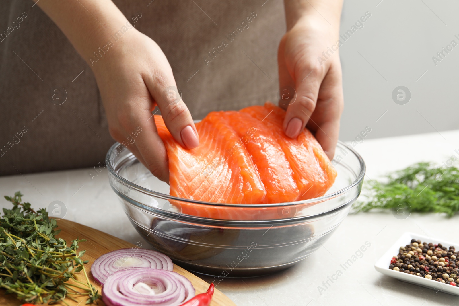 Photo of Woman with salmon fillet and soy sauce at gray table, closeup