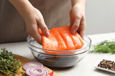 Photo of Woman with salmon fillet and soy sauce at gray table, closeup