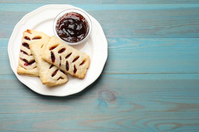 Photo of Delicious puff pastries and jam on light blue wooden table, top view. Space for text