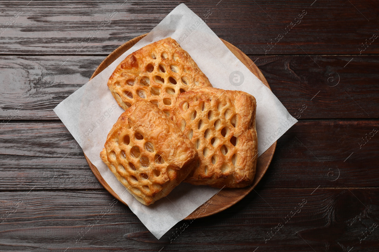 Photo of Delicious puff pastries with fruit filling on wooden table, top view