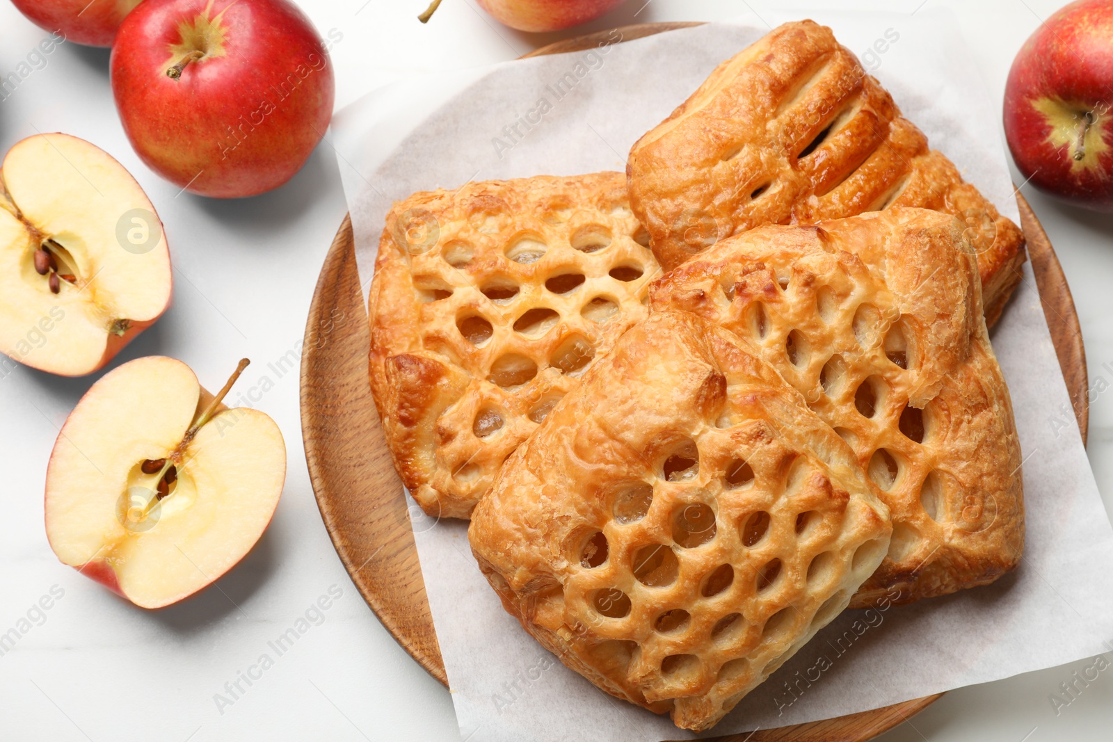 Photo of Delicious puff pastries and apples on white marble table, top view