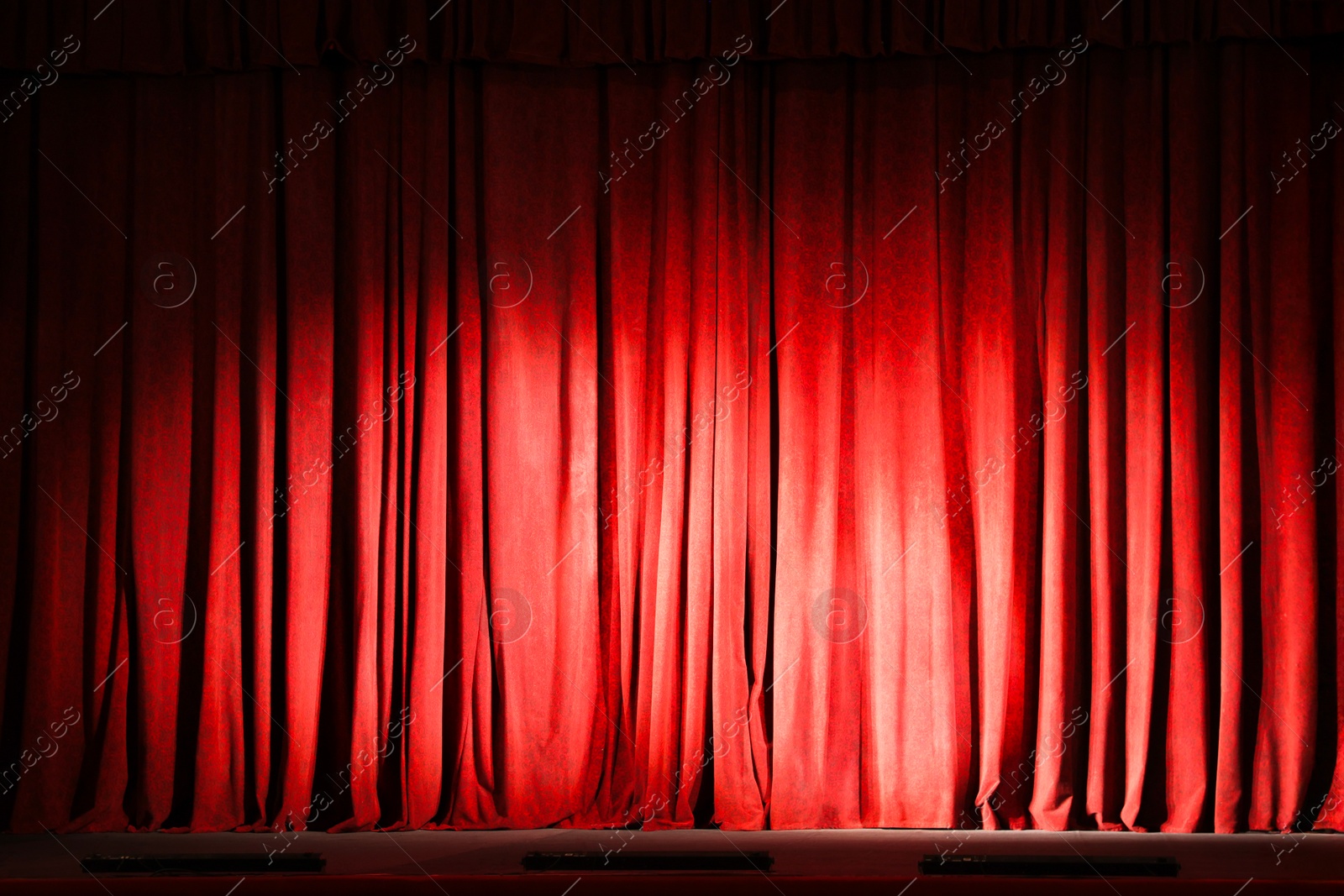 Photo of Elegant closed red curtains illuminated by spotlight in theatre