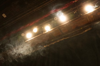 Photo of Professional spotlights and smoke on stage in theatre, low angle view