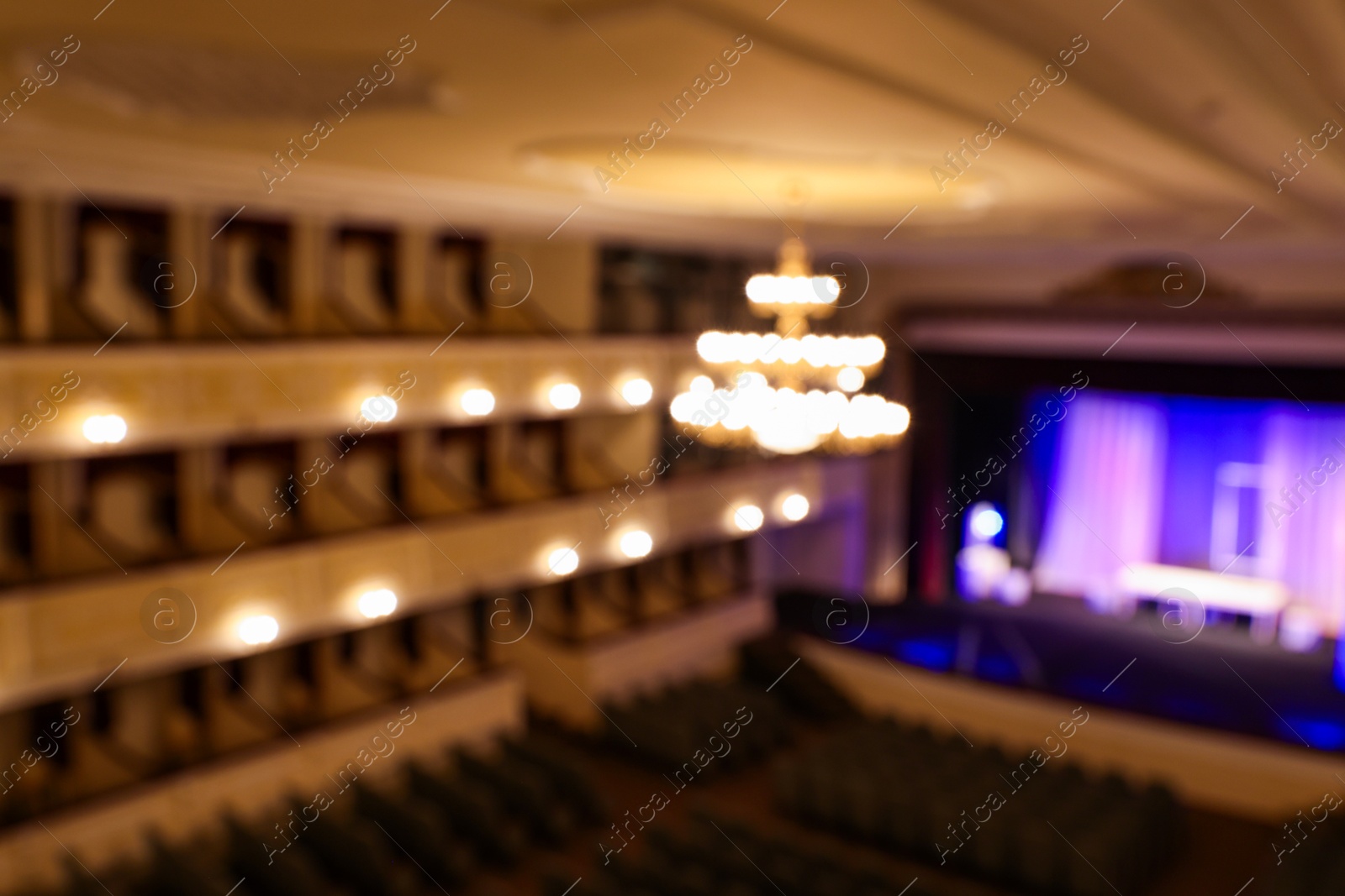 Photo of Blurred view of theatre interior with stage, comfortable seats and beautiful chandelier