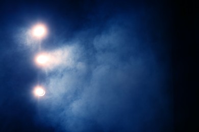 Photo of Professional spotlights and smoke on stage in theatre