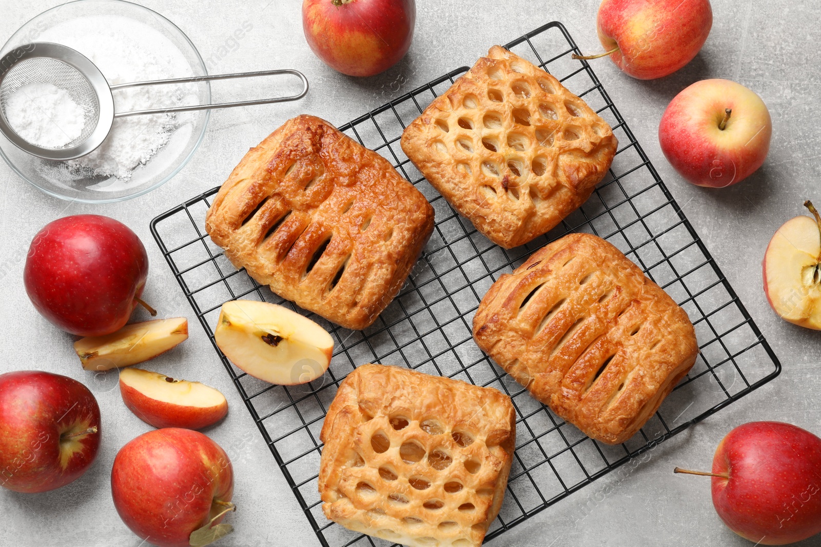 Photo of Delicious puff pastries with fruit filling and apples on grey table, top view